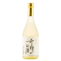 A traditional Japanese sake bottle with a white label featuring black and red calligraphy, a gold neck collar, and a pale yellow liquid, set against a plain white background.